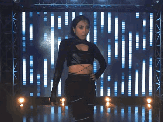 a woman in a black crop top is standing in front of a wall of lights