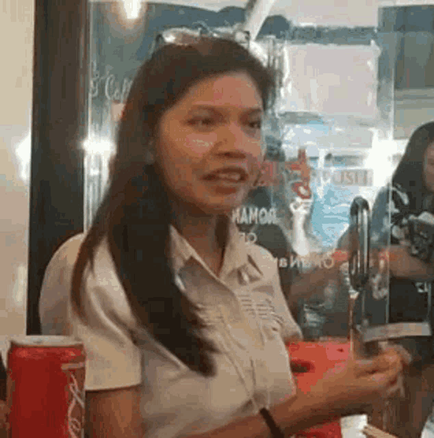 a woman in a white shirt is sitting at a table in a restaurant holding a glass .