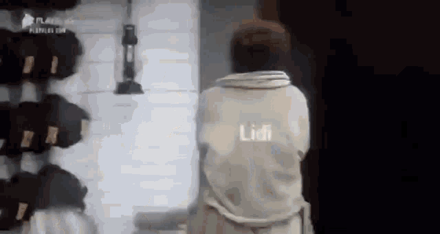 a man in a robe is standing in front of a wall with a lantern .