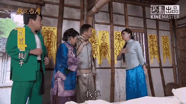 a group of people are standing in front of a wall that has chinese writing on it