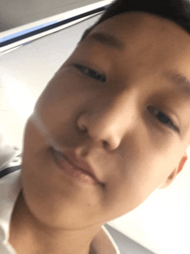 a close up of a young man 's face with a white shirt on