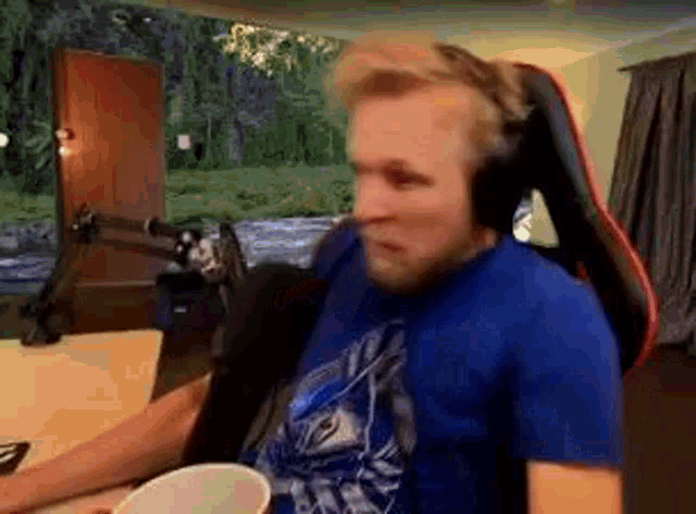 a man wearing headphones and a blue shirt is sitting in a chair .