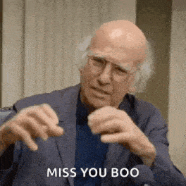 a bald man in a suit and glasses is saying `` miss you boo '' while making a funny face .