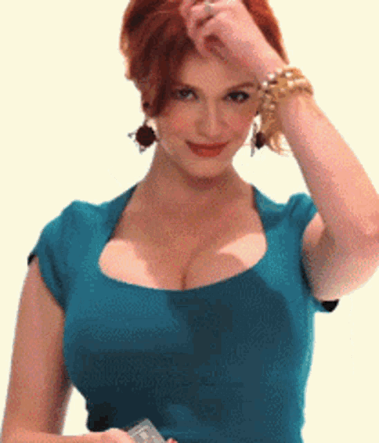 a woman wearing a blue top and a gold bracelet holds her hand to her forehead
