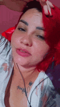a woman with red hair and a tattoo on her chest is wearing headphones .