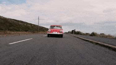 a red car is driving down a road with a license plate that says tfsj