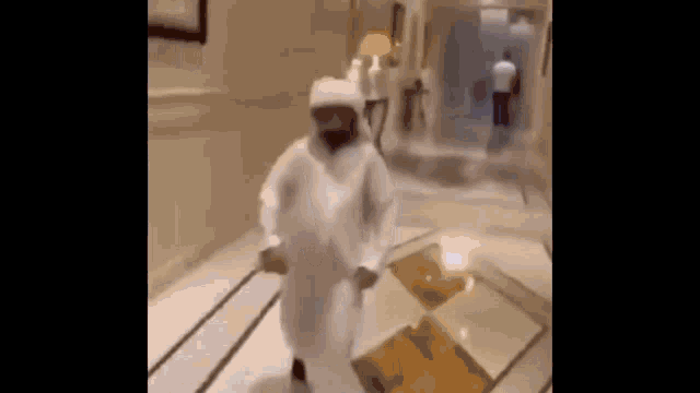 a man in a white robe is dancing in a hallway in a house .