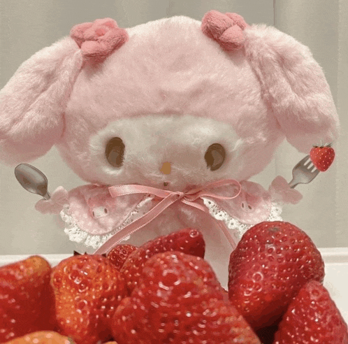 a stuffed animal is holding a spoon and fork and a strawberry