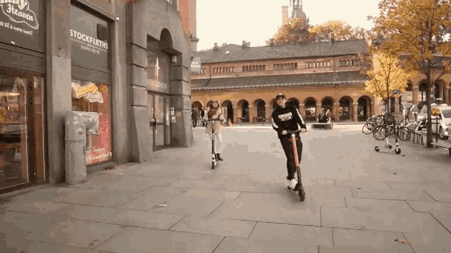 a woman riding a scooter in front of a store called stockfleting