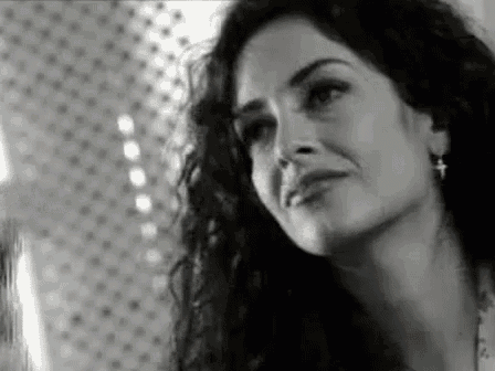 a black and white photo of a woman with long curly hair and earrings .