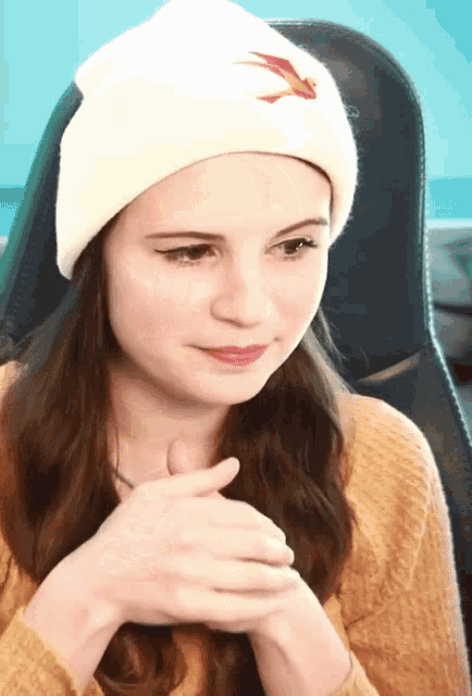 a woman wearing a white beanie with a red bird on it