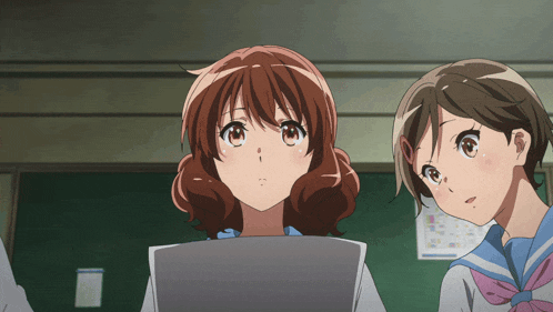 two anime girls are looking at something in front of a blackboard