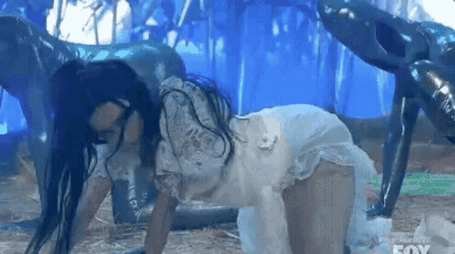 a woman in a white dress is crawling on the ground with a fox logo in the background