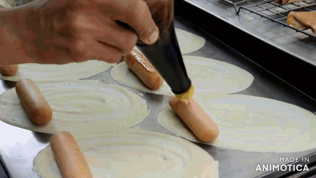 a person is spreading a sauce on hot dogs on a tray made in animatica