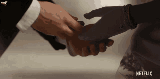 a man and a woman are shaking hands with a netflix logo in the corner