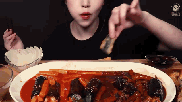 a woman is eating a large plate of food with chopsticks ..