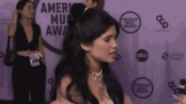 a woman is standing on a purple carpet at an event .