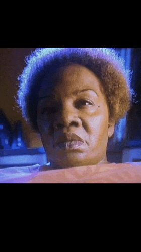 a close up of a woman 's face with a purple light behind her