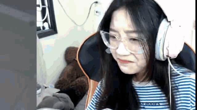a girl with glasses and headphones is sitting in a chair .
