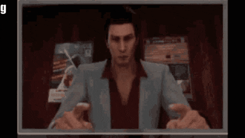a man in a suit and red shirt is pointing at the camera with the word gm on the screen .
