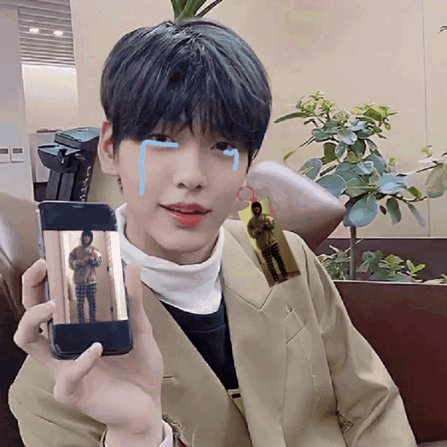 a young man is holding up a cell phone with a picture of a man on it