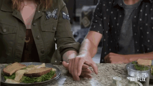 a man and a woman holding hands in front of a plate of food with netflix written on the bottom