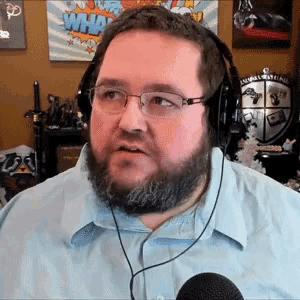 a man with a beard and glasses is wearing headphones and a microphone .