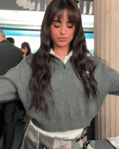 a woman wearing a grey sweater and a white shirt has a belt around her waist that says abercrombie & fitch