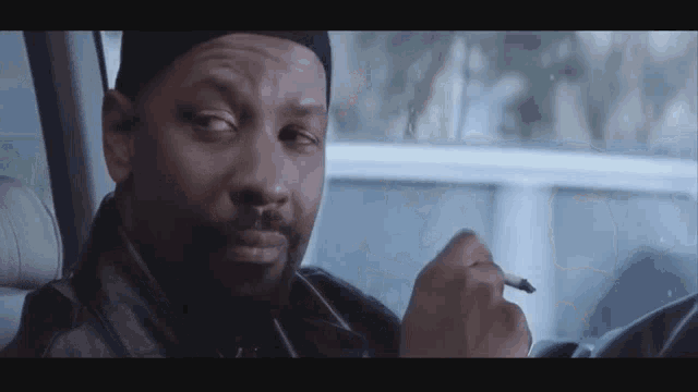 a man with a beard is smoking a cigarette in a car
