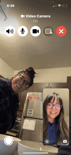a phone screen shows two people on a video call and the video camera is on