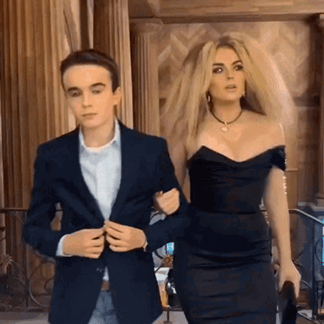 a man in a suit and a woman in a black dress walk together