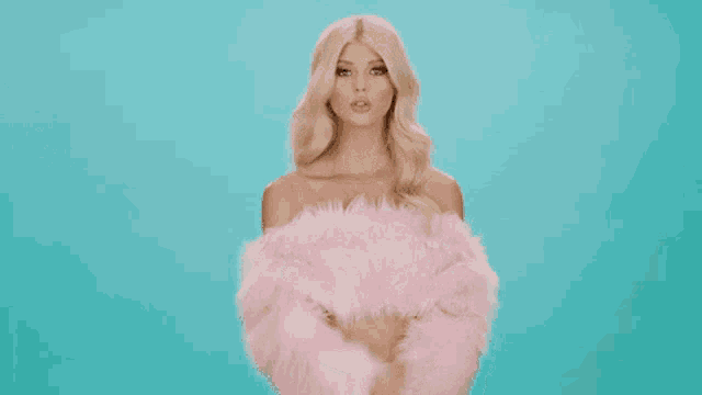 a woman in a pink fur coat is blowing a kiss to the camera .