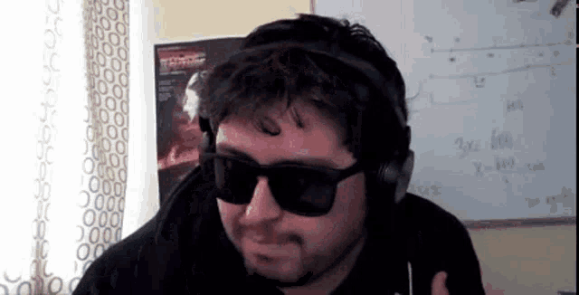 a man wearing headphones and sunglasses is standing in front of a whiteboard with a math problem on it .