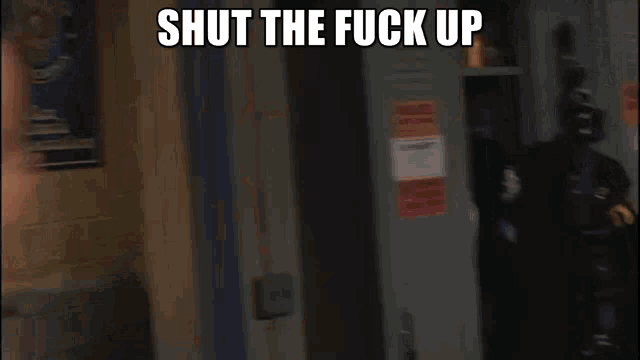 a blurry picture of a man standing in front of lockers with the words shut the fuck up above him