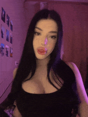 a woman with long black hair is wearing a black tank top and a nose ring