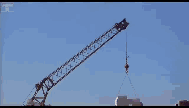 a man in a purple sweater is standing on top of a roof with his arms outstretched .