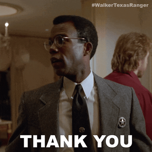 a man in a suit and tie is giving a thank you sign