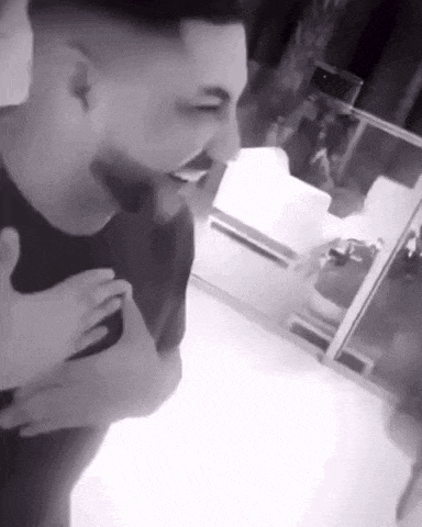 a man is laughing in a black and white photo while holding another man 's hand .