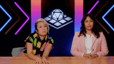 two women are sitting at a table in front of a cube .