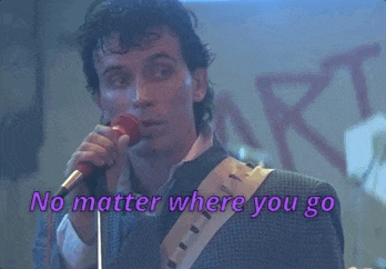 a man singing into a microphone with the words no matter where you go behind him