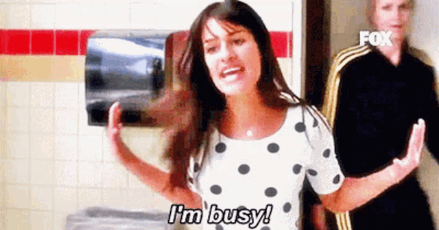 a woman in a polka dot shirt is saying `` i 'm busy '' .