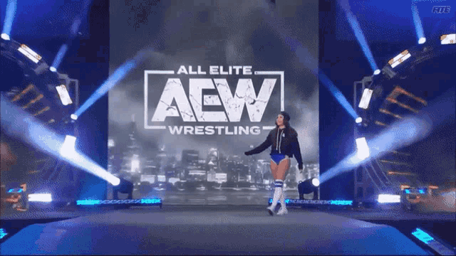 a woman is walking on a stage in front of an all elite aew wrestling sign