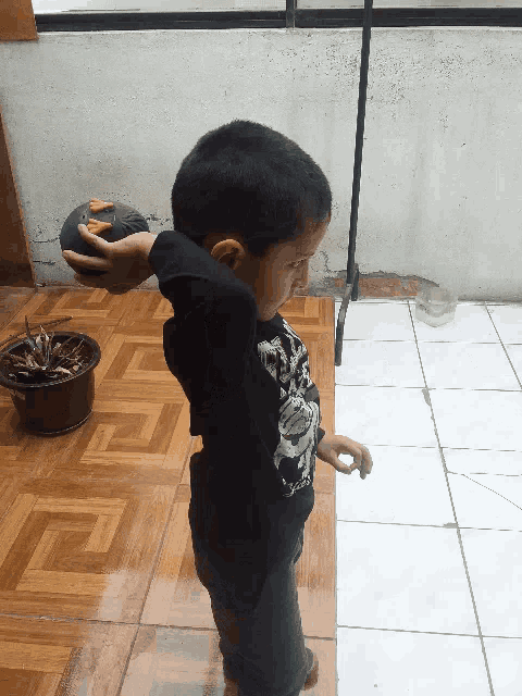 a young boy wearing a black shirt with a skull on it is standing on a tiled floor
