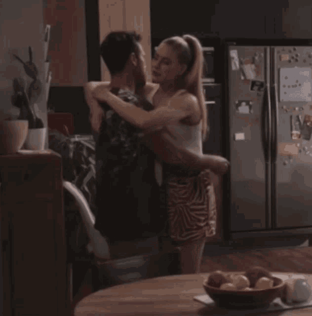 a man and a woman hugging in front of a fridge