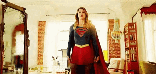 a woman in a superman costume is standing in a living room .