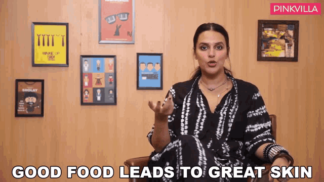 a woman is sitting in front of a wall with framed pictures and the words good food leads to great skin above her