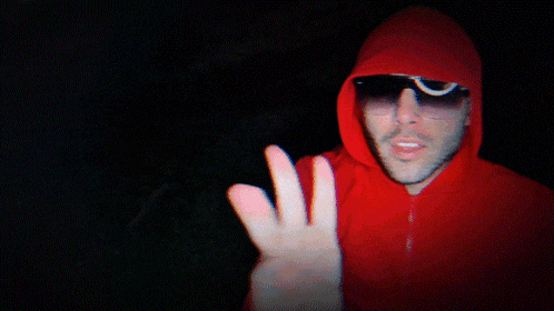 a man wearing a red hoodie and sunglasses is making a peace sign