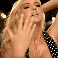 a blonde woman in a black and white polka dot dress is making a funny face .