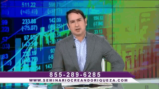 a man in a suit stands in front of a screen that says seminariocreandoriqueza.com on it