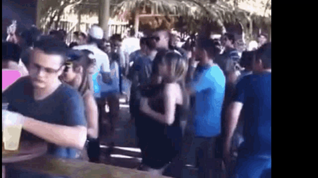a group of people are standing around a table in a crowded room at a party .